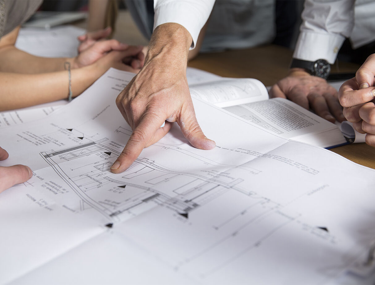 Team reviewing architectural glazing plans and blueprints